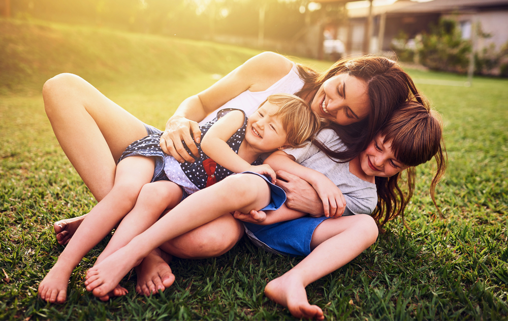 Shot of a mother bonding with her two adorable little children outdoors.